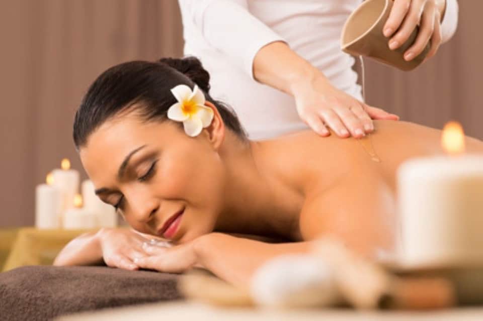 Spa massage treatment with relaxed woman receiving back massage in candlelit room