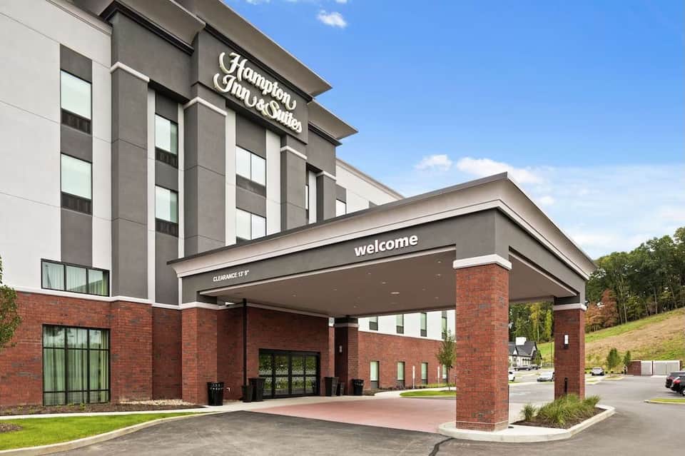 Hampton Inn & Suites entrance with brick facade, modern signage, welcoming entrance, and parking