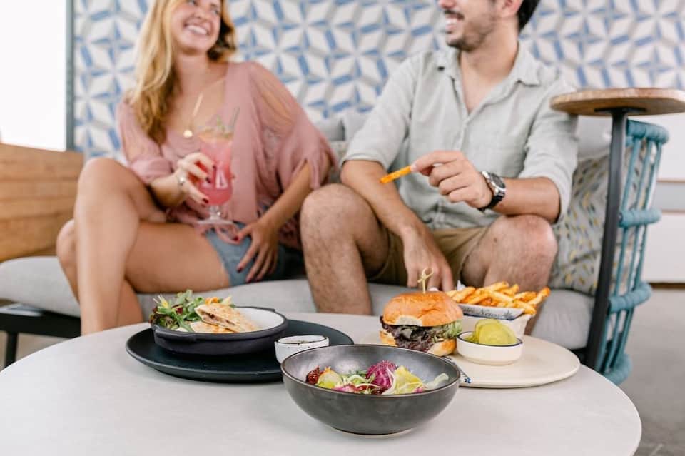 Couple dining poolside with gourmet food and beverages, enjoying casual resort atmosphere