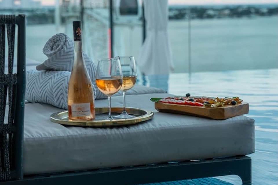 Rosé wine and charcuterie board on lounge by infinity pool overlooking water