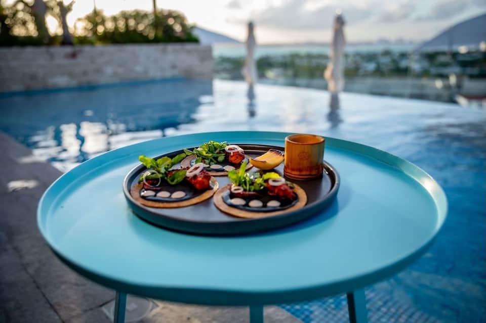 Gourmet appetizers on turquoise table by resort pool with mountain views