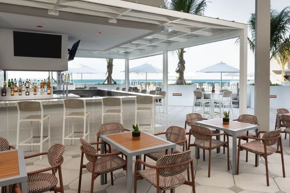 Upscale beachside bar and restaurant with ocean views and white pergola structure