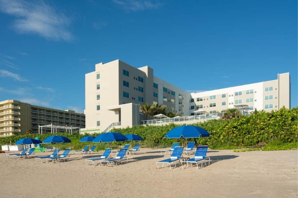 Beachfront hotel with blue umbrellas and lounge chairs on sandy shore