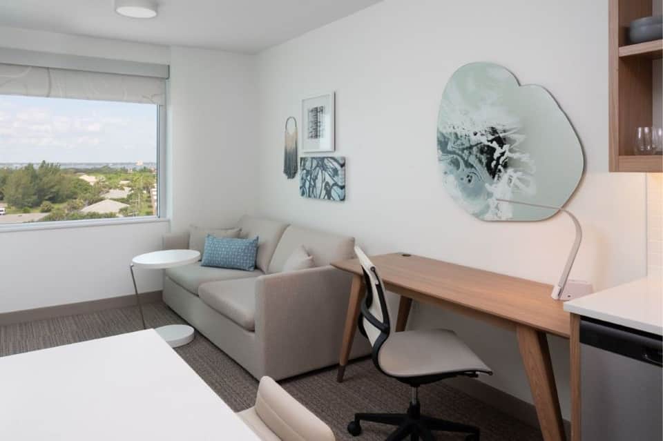 Modern hotel room interior with window view, neutral furnishings, and work desk