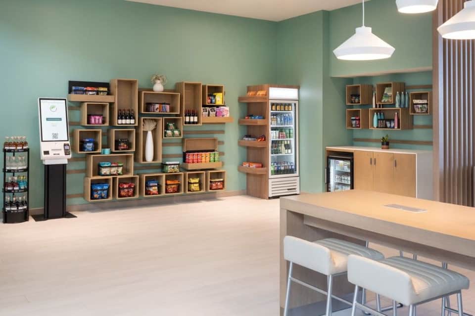 Contemporary café interior with mint green walls, wooden shelving, counter seating, and refreshment displays