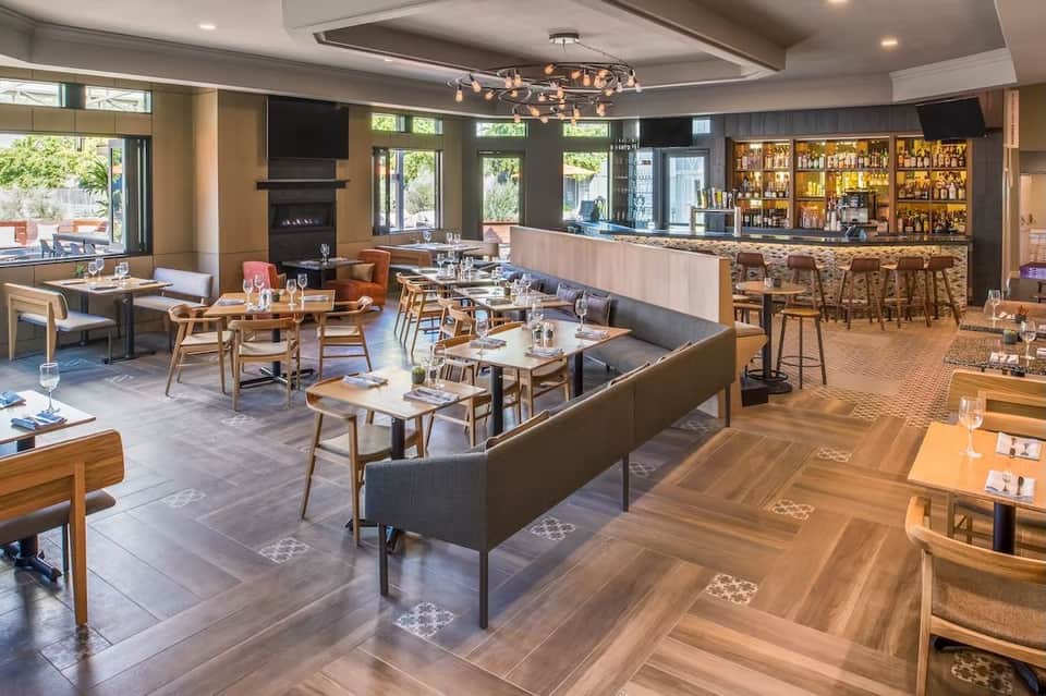 Modern restaurant and bar interior with wooden furniture, fireplace, and well-stocked liquor shelves