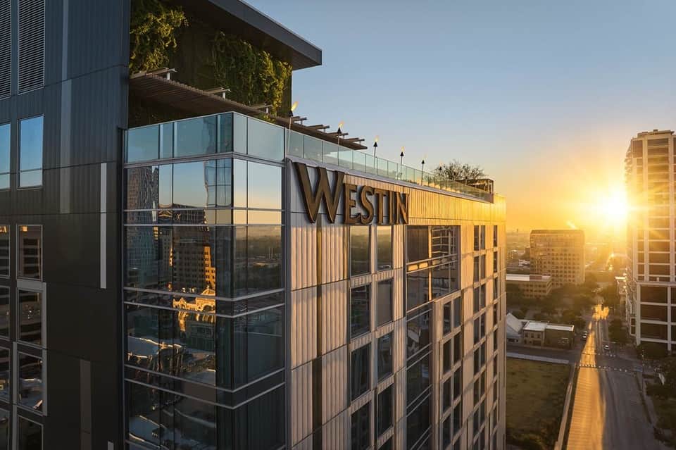 Modern Westin hotel building at sunset with glass façade and city skyline