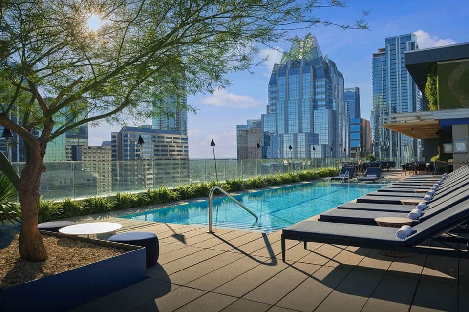 Resort pool with landscaping and loungers facing downtown skyline and water