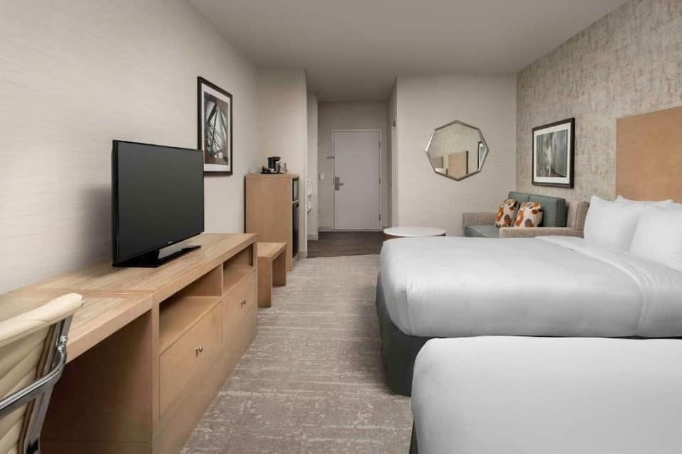 Hotel room with two queen beds, TV, wooden furniture, and modern bathroom