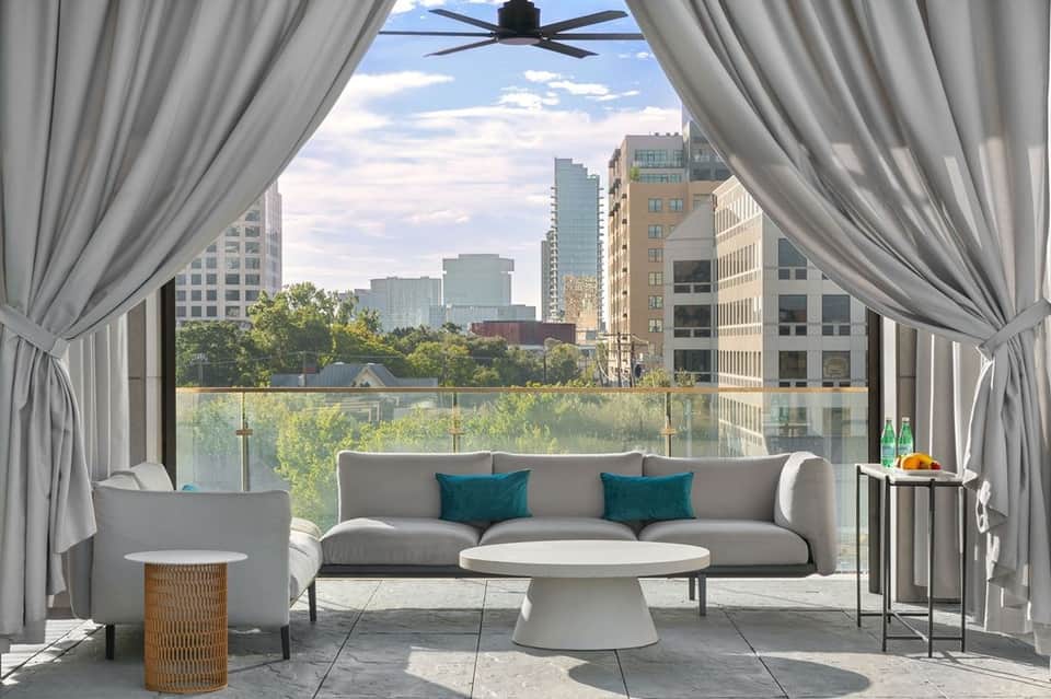 Modern terrace lounge with gray sofa, sheer curtains, and expansive city skyline views