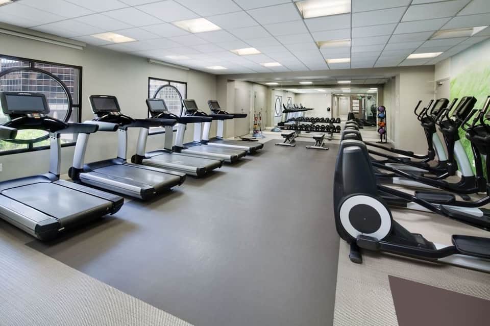 Large fitness room with treadmills, elliptical machines, weights, and exercise equipment