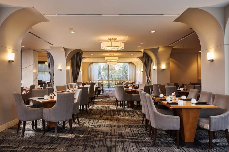 Elegant hotel dining room with arched ceilings, warm lighting, and wooden tables