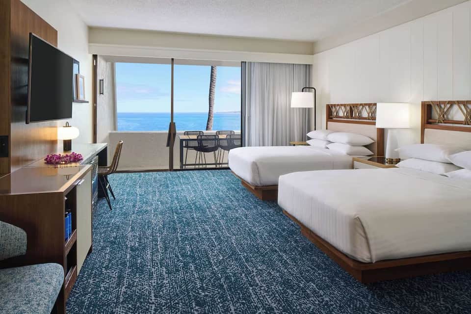 Beachfront double queen room with ocean view balcony, modern décor, and TV