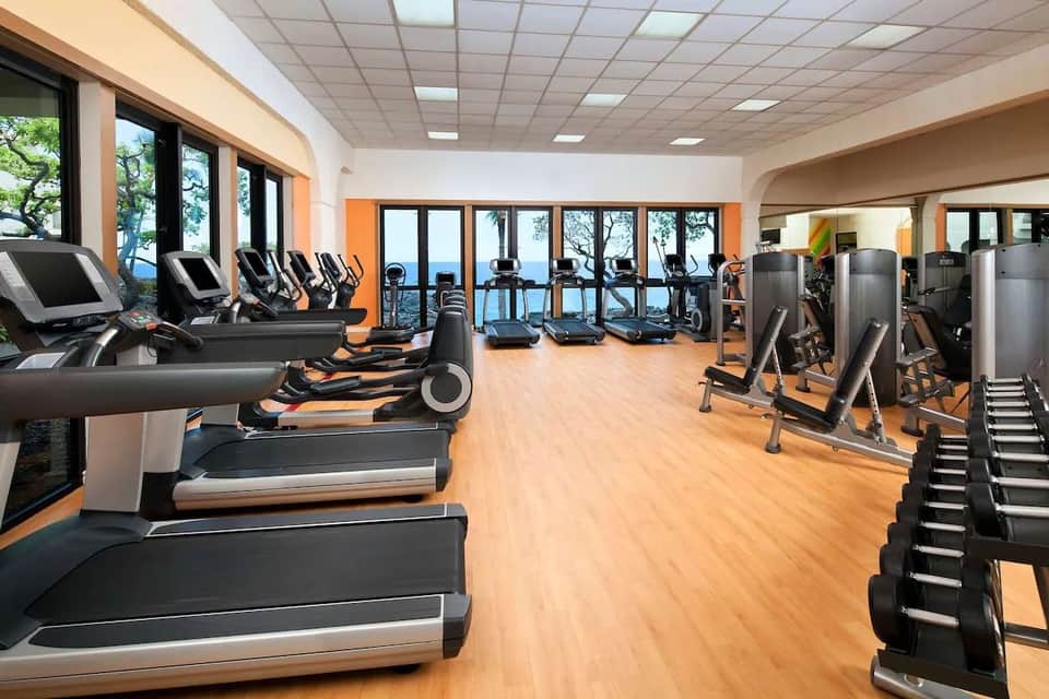 Modern fitness center with cardio equipment and ocean views through large windows