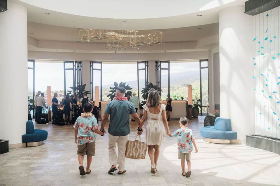 Spacious hotel lobby with curved ceiling, tropical plants, and mountain views