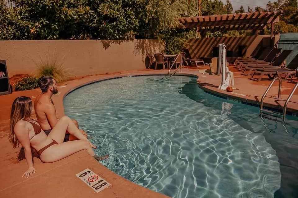 Couple relaxing poolside at resort with lounge chairs and terracotta walls