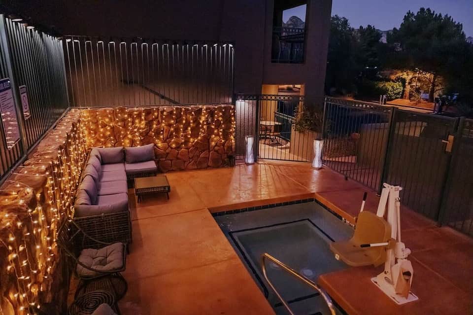 Rooftop courtyard at night with string lights, seating area, and trampoline