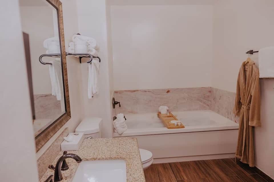 Bathroom with pink marble walls, white sink vanity, and soaking tub