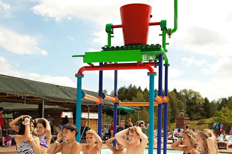 Colorful water dumping bucket playground attraction with children in swimwear underneath