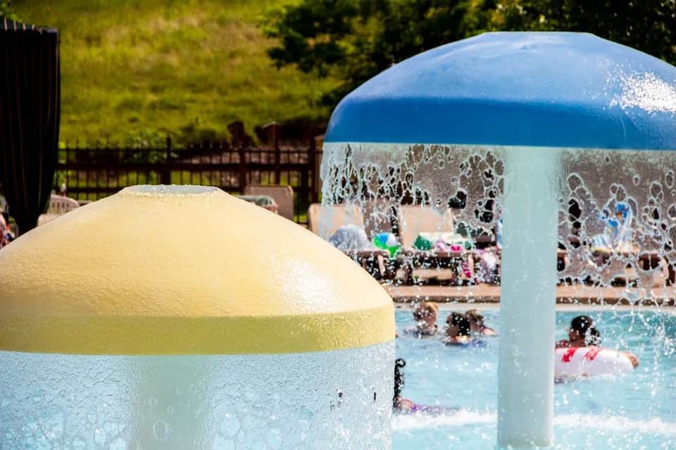 Outdoor water splash pad with yellow and blue dome structures and children playing