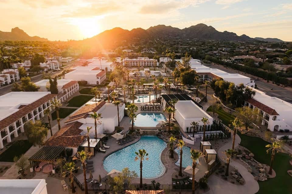 Aerial sunset view of luxury resort with multiple pools and palm tree landscaping