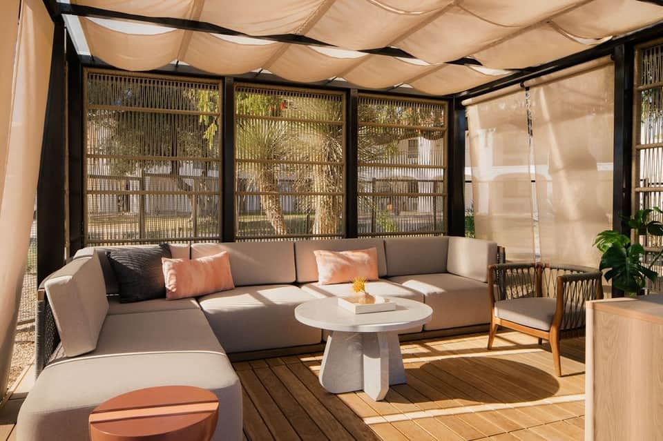 Modern poolside lounge area with curved sofa, shade sail, and geometric screens
