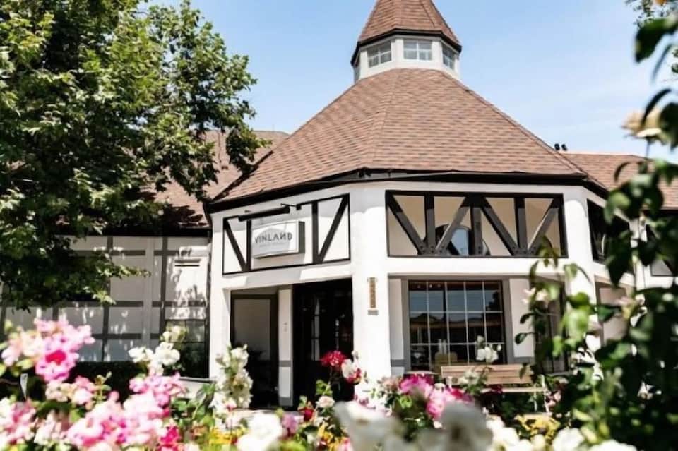 Tudor-style building with peaked roof, decorative half-timbering, and pink flowers