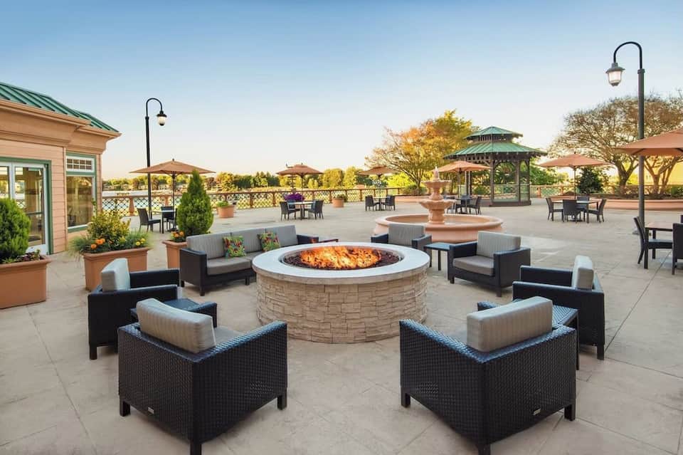 Expansive outdoor terrace with multiple fire pits, lounge seating, umbrellas, and lush landscaping