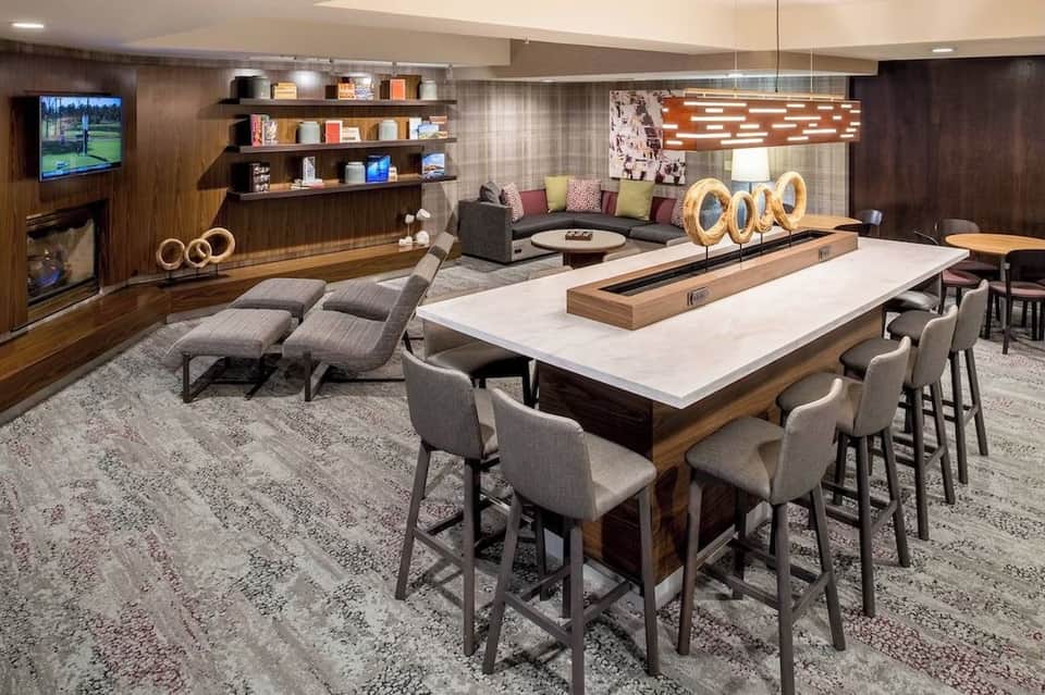 Upscale game room and lounge with pool table, lounge seating, fireplace, shelving, and casual dining bar