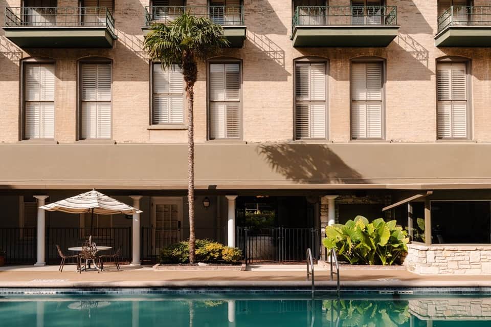 Waterfront hotel pool with brick building facade and ground-level patio seating