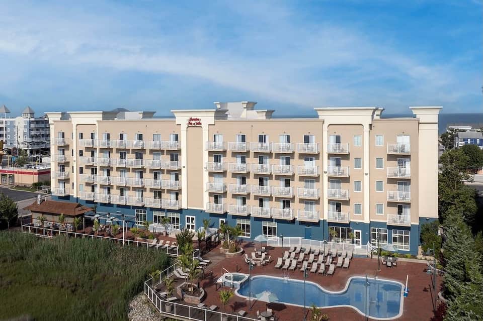 Beachfront resort building with cream facade, blue ground level, and curved pool
