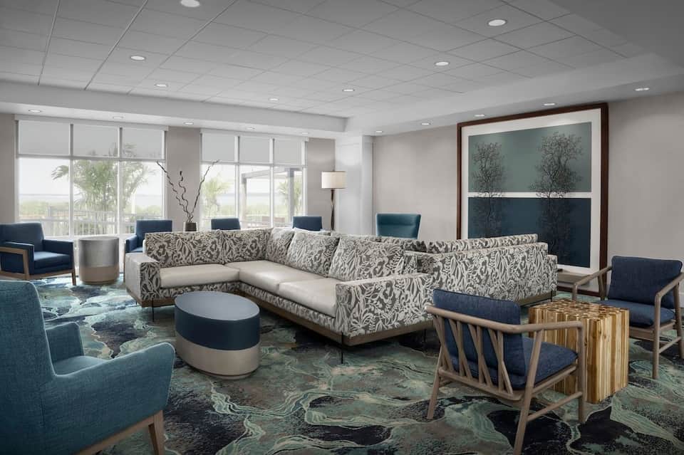 Bright hotel lounge with sectional sofa, accent chairs, and panoramic bay windows