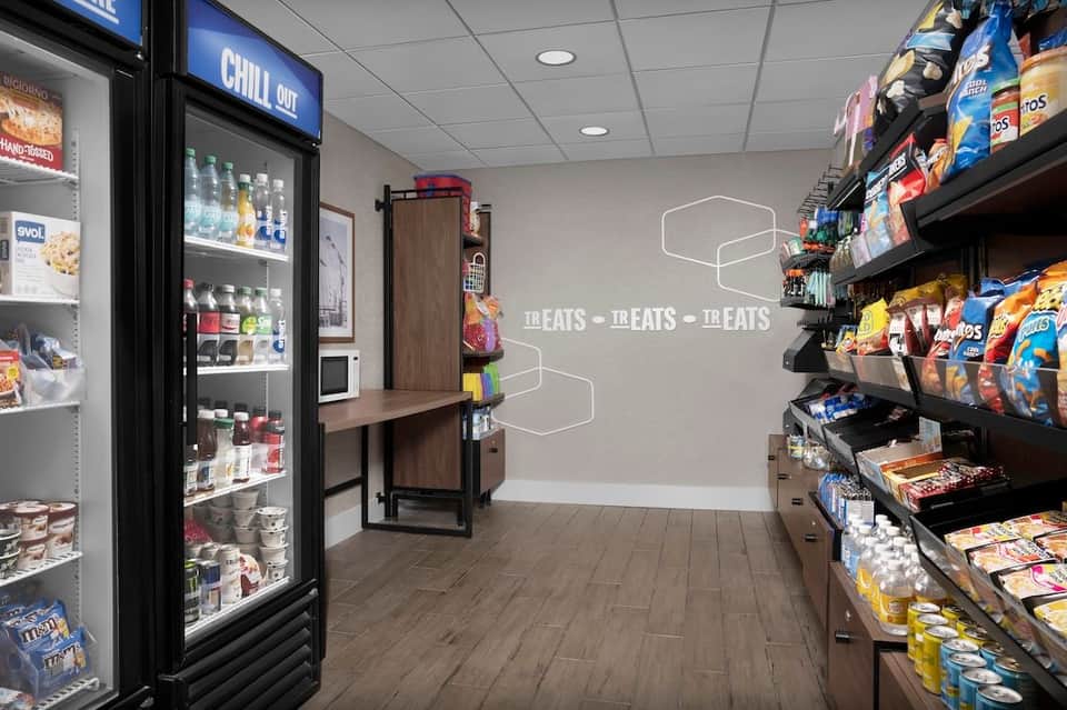 Hotel convenience store interior with refrigerated beverages and snack shelves