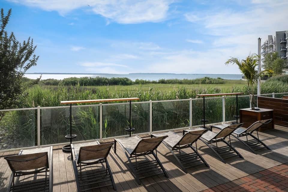 Waterfront deck with lounge chairs overlooking marshland and bay water