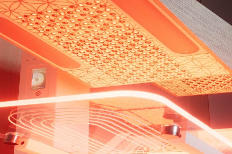 Close-up of red neon-lit infrared sauna ceiling with geometric patterns