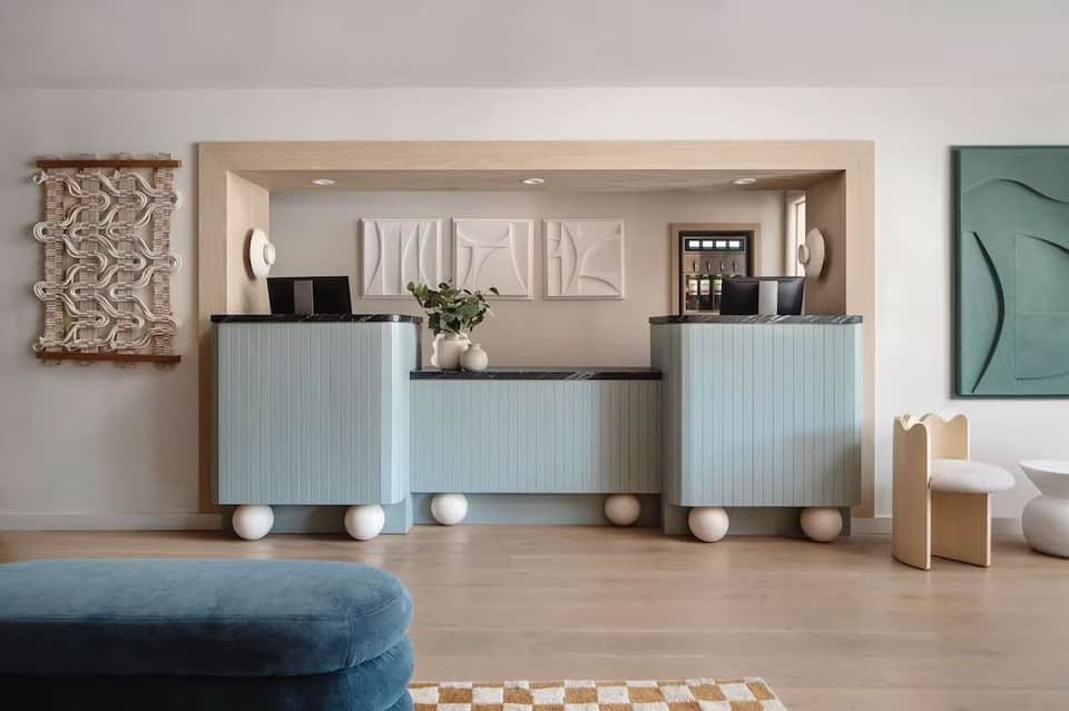 Modern hotel reception desk with light blue paneling, white spherical decorative elements, and contemporary wall art