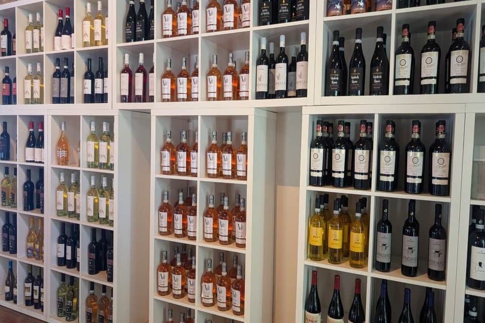 Wine cellar wall displaying bottles of red, white, rosé, and dark wines