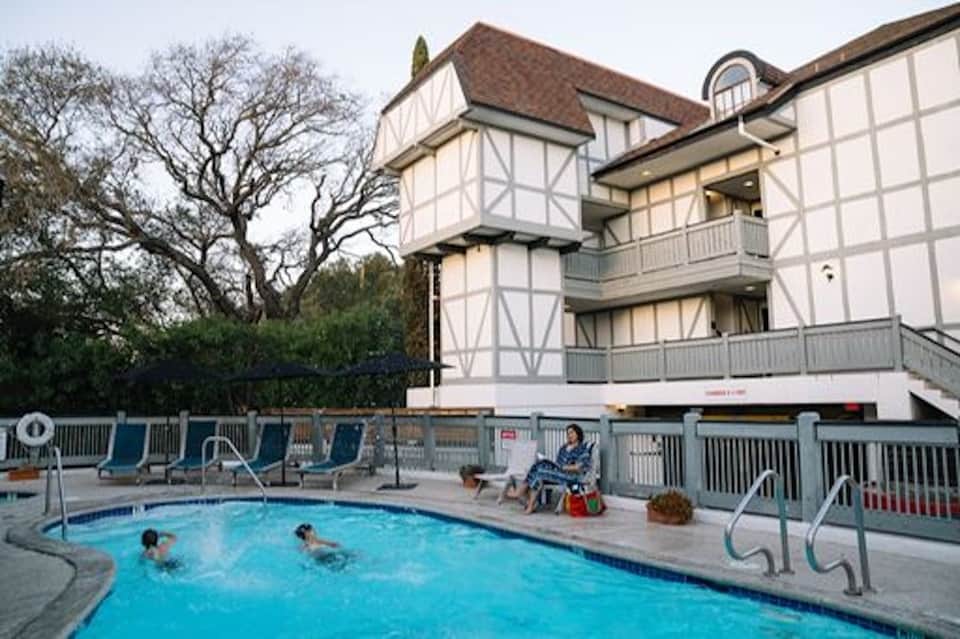Tudor-style hotel building with outdoor swimming pool and blue lounge chairs
