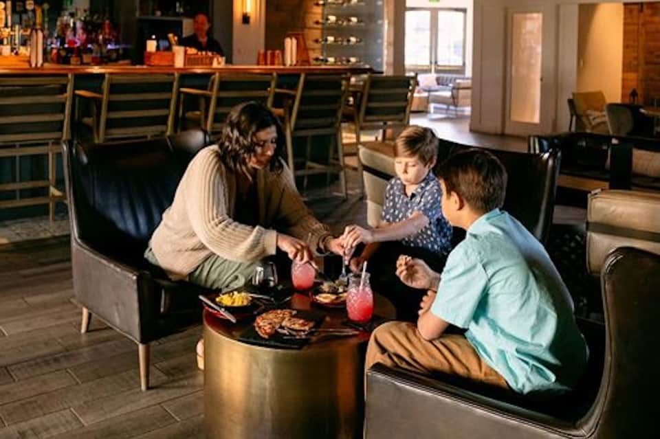 Family with children enjoying drinks and food in modern hotel lounge