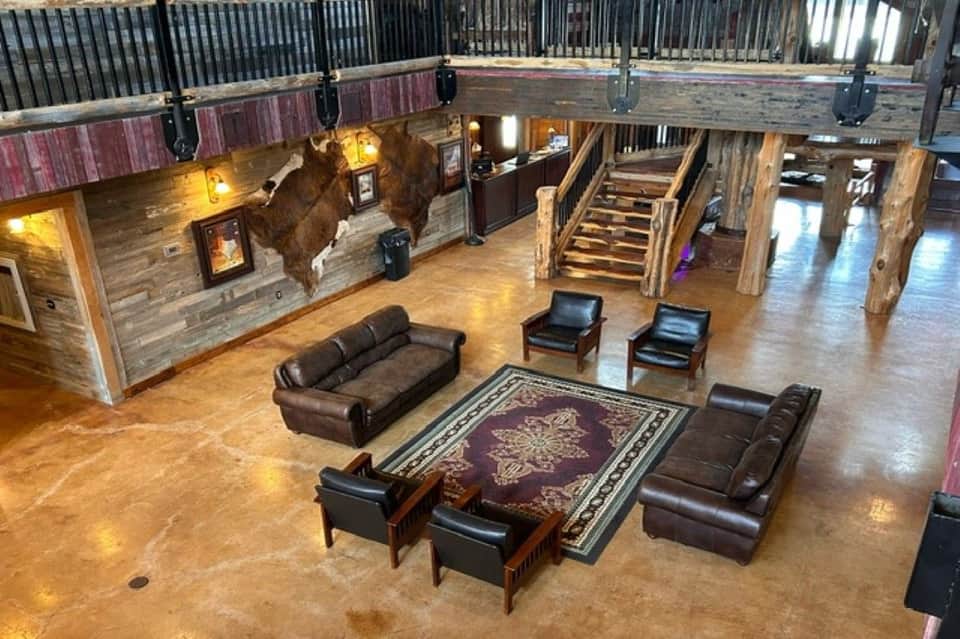 Rustic indoor lounge with wooden beams, leather seating, taxidermied bull head on wall, and polished concrete floors