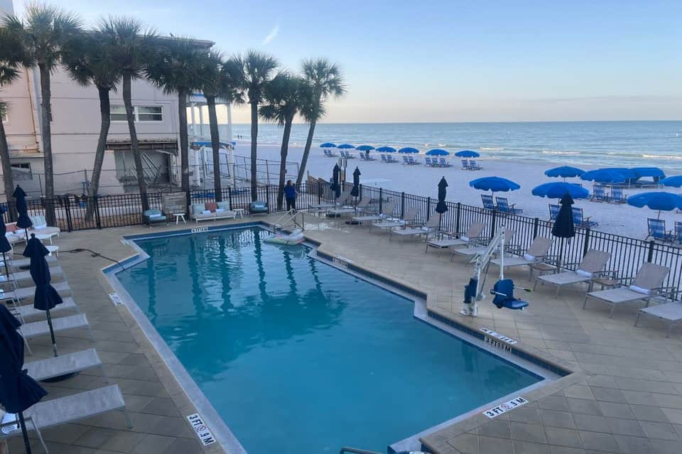 Resort pool and deck area with swimming pool, loungers, umbrellas, ocean view, and palm trees