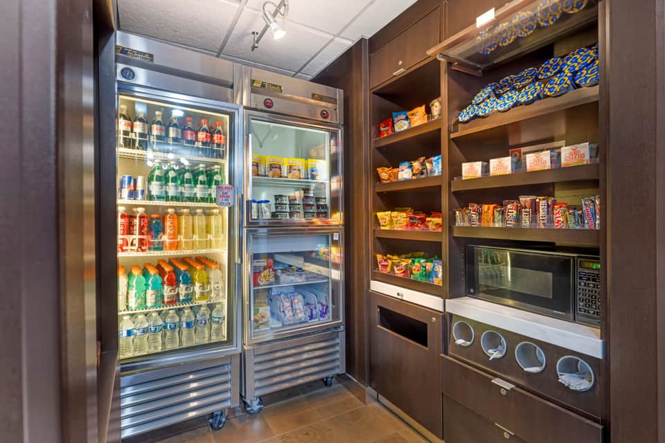 Convenience market with refrigerated beverage display, snack shelves, microwave, and supplies