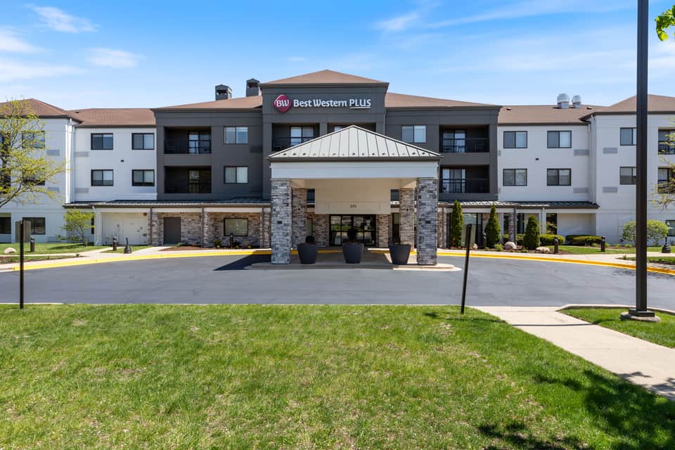 Best Western PLUS hotel exterior with stone entrance, manicured lawn, and modern architecture