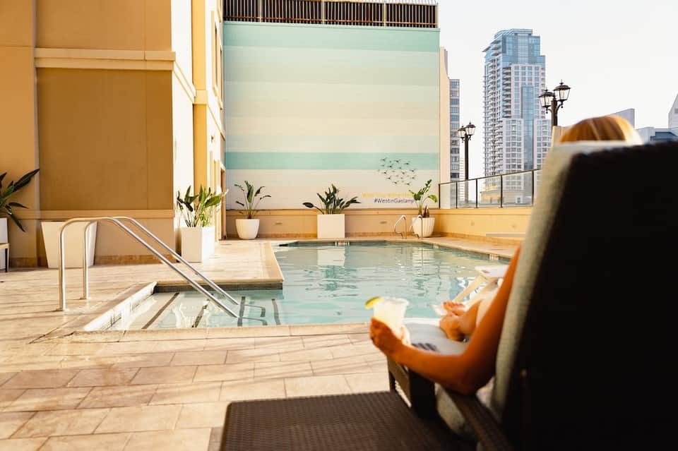 Rooftop pool area with city skyline views, lounge seating, and modern architectural elements
