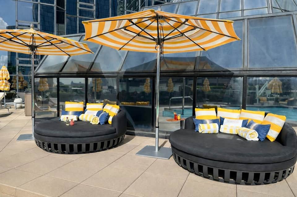 Outdoor pool deck with round sunbeds under yellow-striped umbrellas and contemporary lounge seating