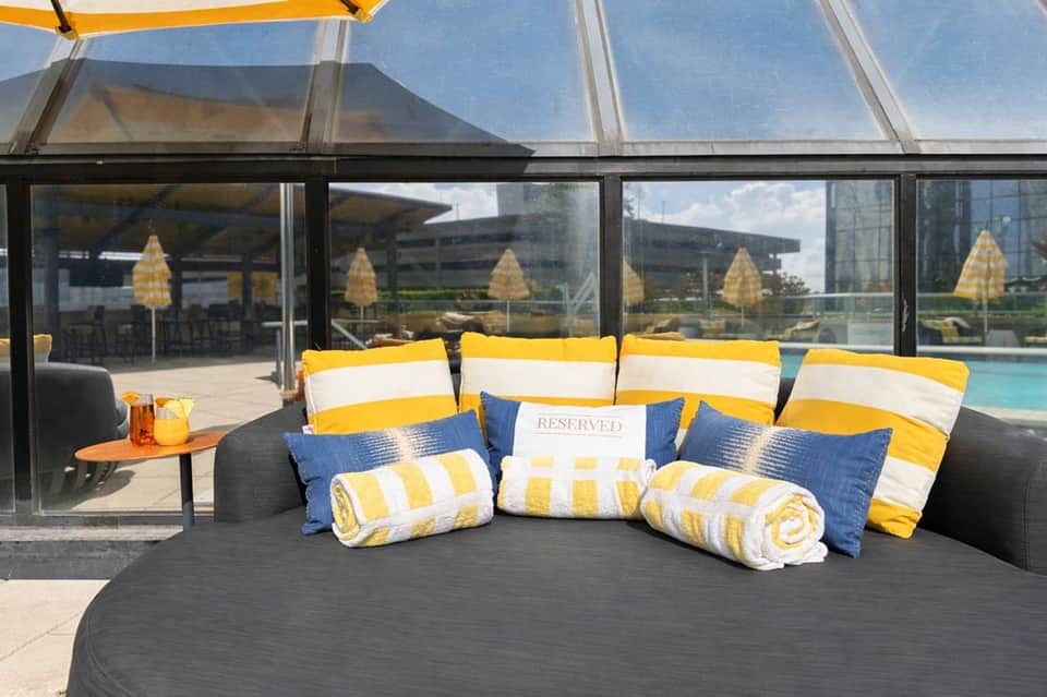 Reserved circular sunbed with yellow-white striped cushions and pillows overlooking pool area