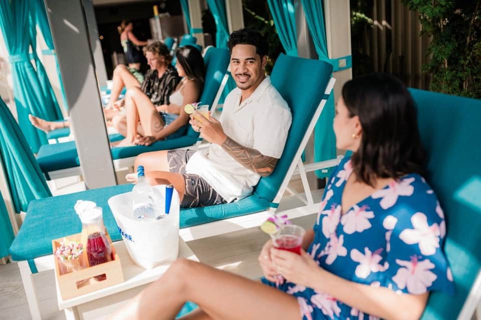 Couple relaxing in teal cabanas with beverages and snacks at resort