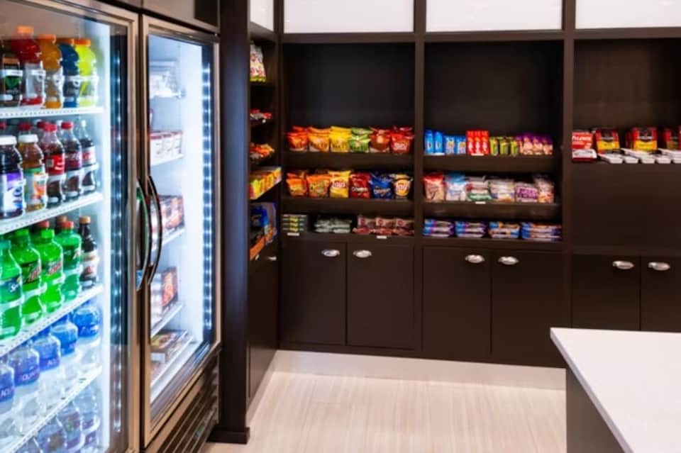 Hotel convenience store with refrigerated beverages and shelving stocked with snacks and drinks