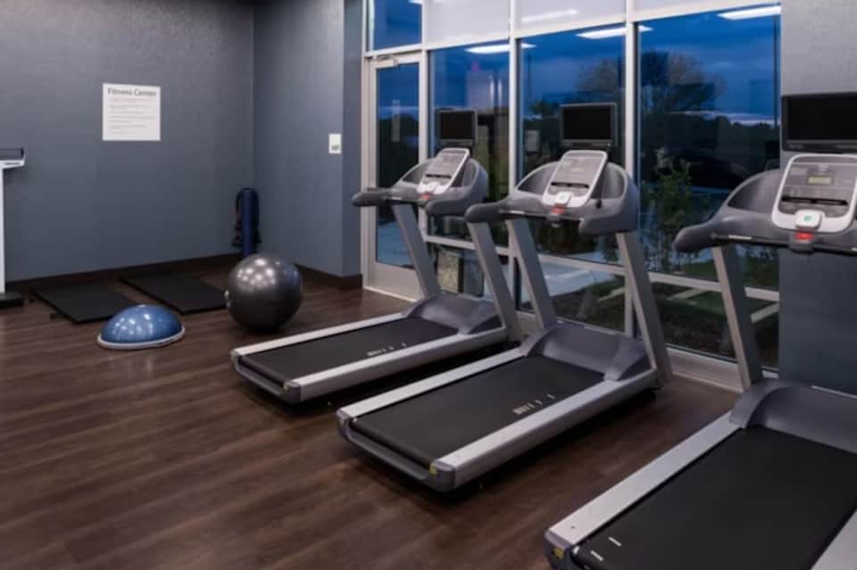 Modern fitness center with treadmills, exercise equipment, wood flooring, and scenic window views