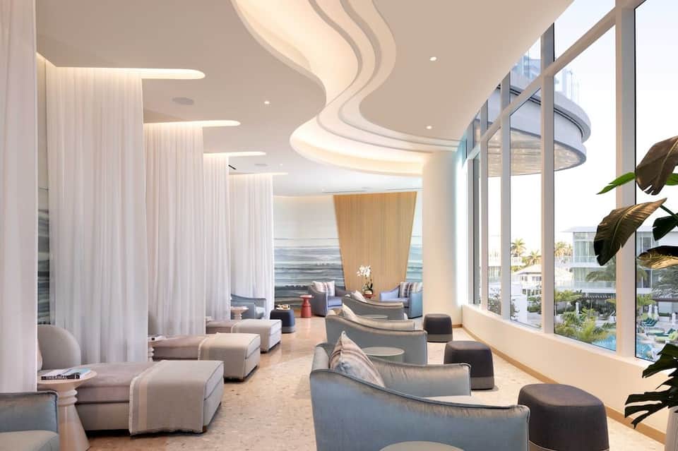 Luxury spa lounge with curved ceiling design, flowing white curtains, and ocean views